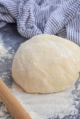 homemade pizza dough on a gray floured surface
