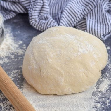 homemade pizza dough on a gray floured surface