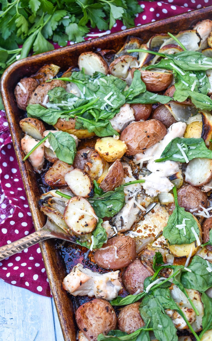 a metal spatula scooping roasted chicken and vegetables off a sheet pan