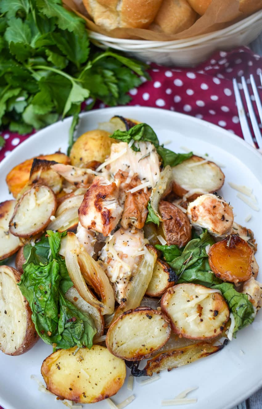 roasted chicken and vegetables on a white plate with a silver fork resting on the side