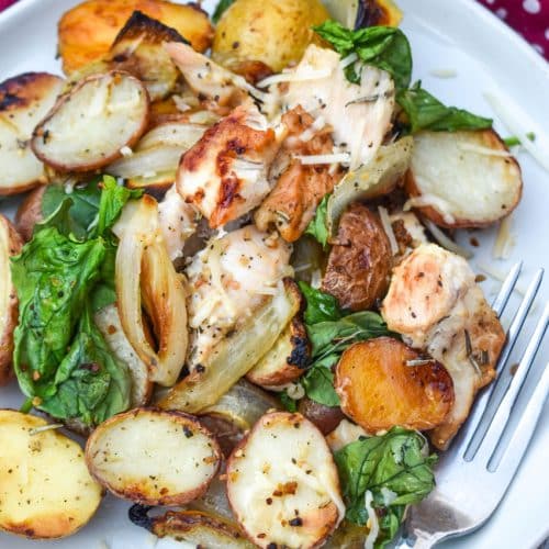 roasted chicken and vegetables on a white plate with a silver fork resting on the side