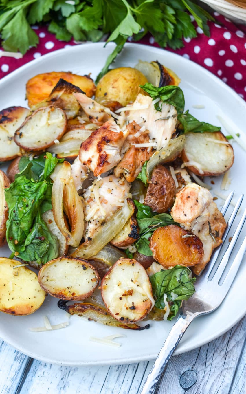 roasted chicken and vegetables on a white plate with a silver fork resting on the side