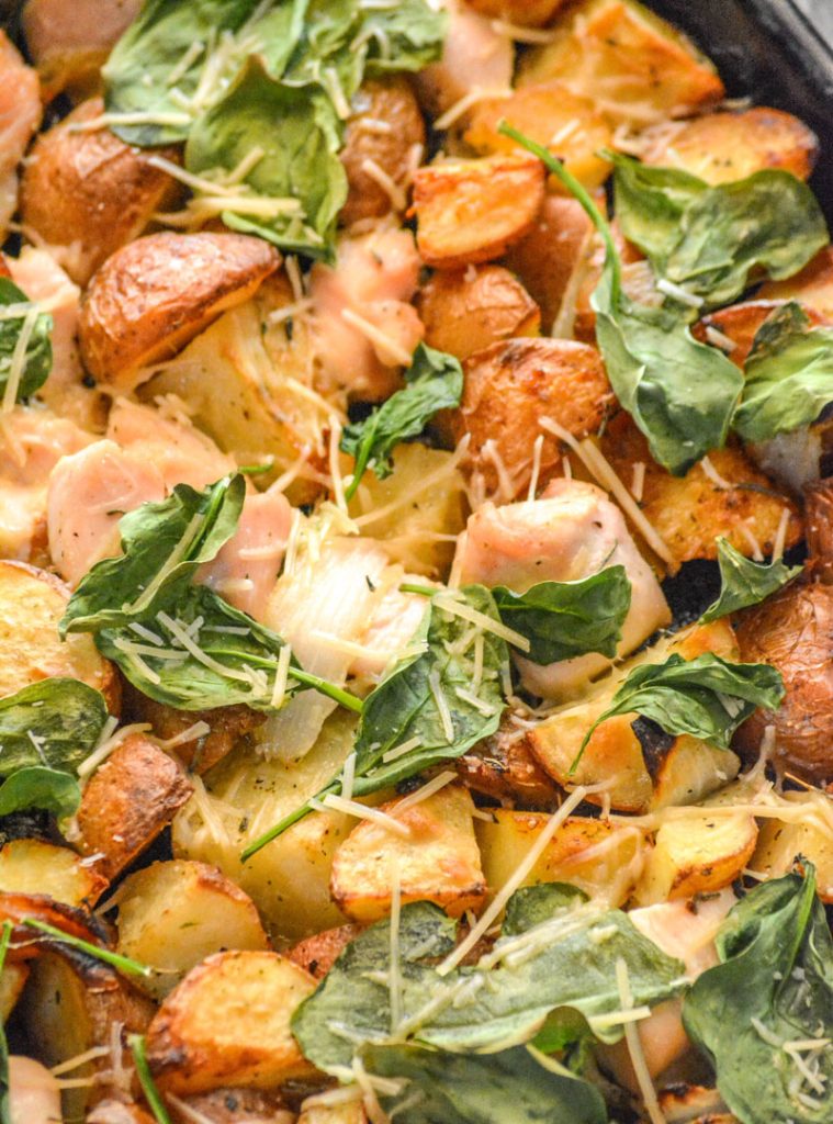 Roasted Chicken and Vegetable Sheet Pan Supper, a close up showing the roasted chicken and potato chunks with crispy spinach leaves topped with shredded Parmesan cheese