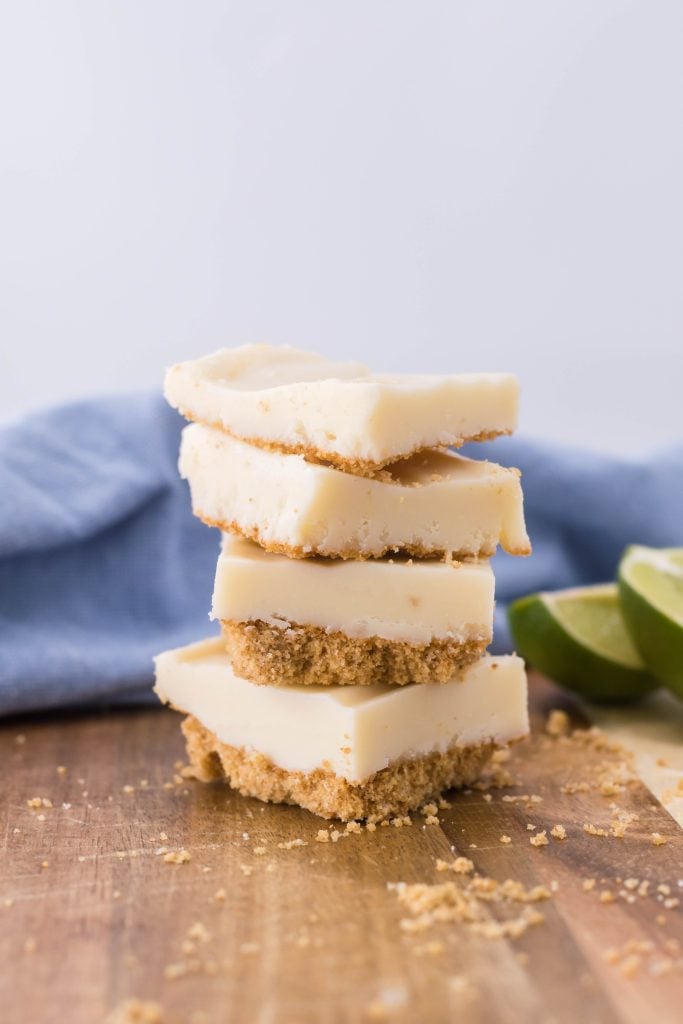 squares of key lime pie fudge stacked on top of each other on a wooden cutting board