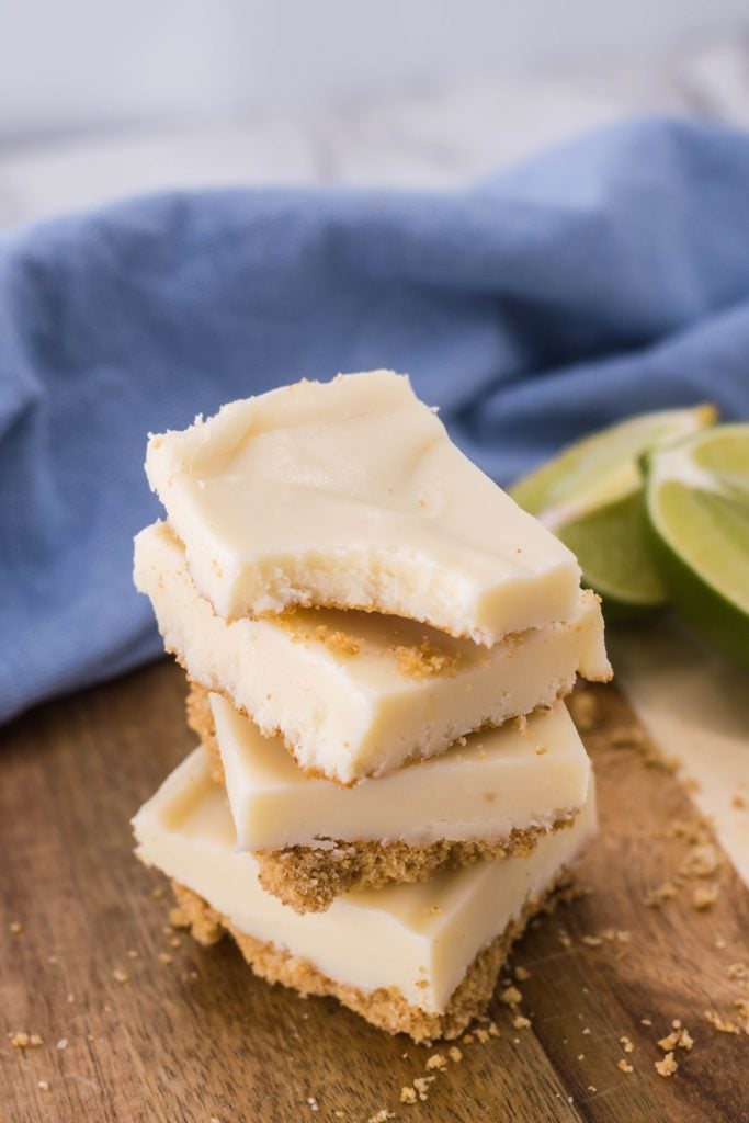 squares of key lime pie fudge stacked on top of each other on a wooden cutting board