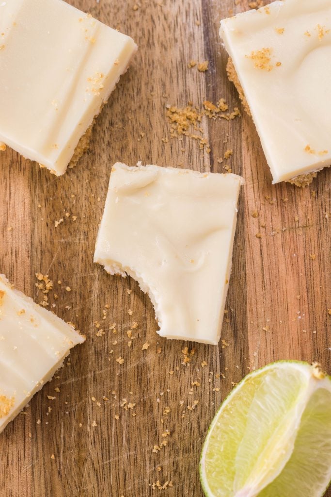 square of key lime pie fudge shown on a wooden cutting board with a lime wedge
