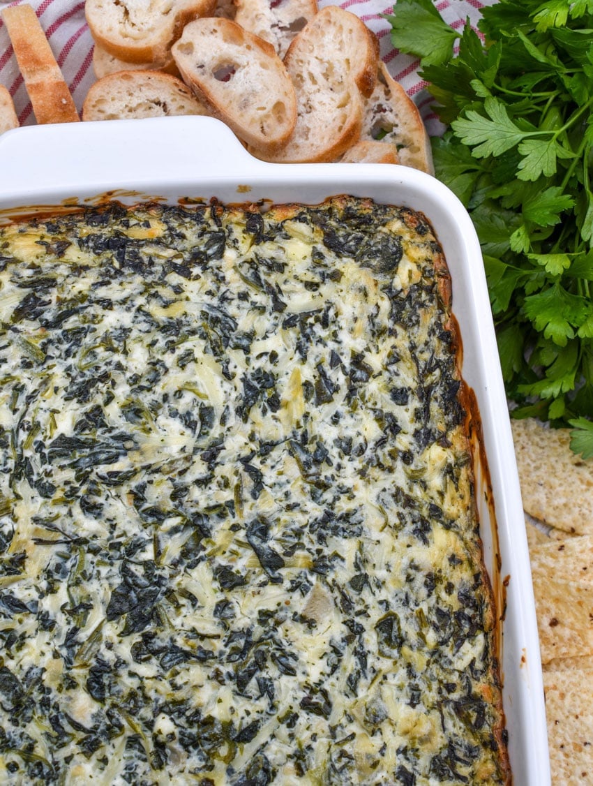 baked creamy spinach and artichoke dip in a white baking dish