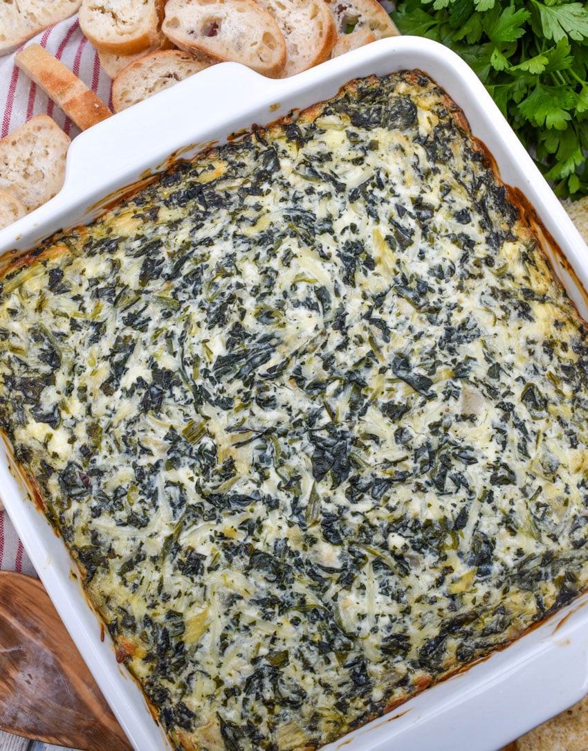 baked creamy spinach and artichoke dip in a white baking dish