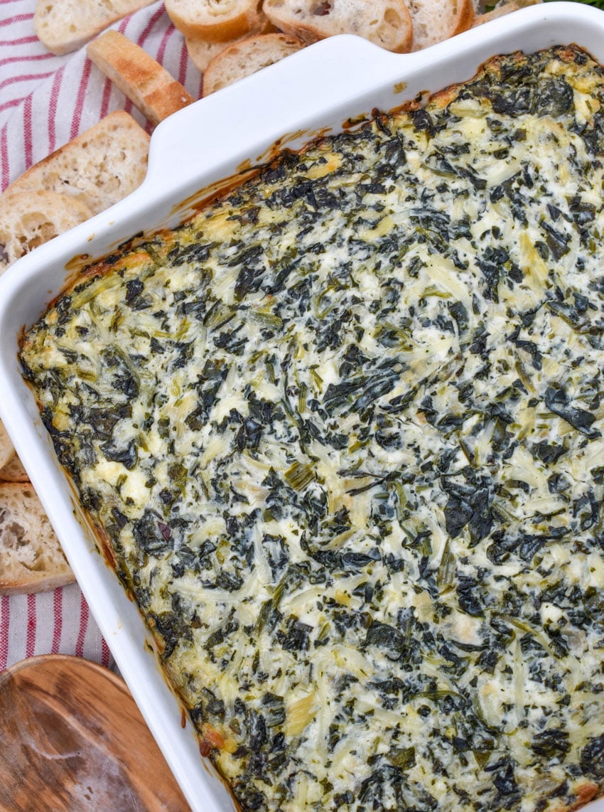 baked creamy spinach and artichoke dip in a white baking dish