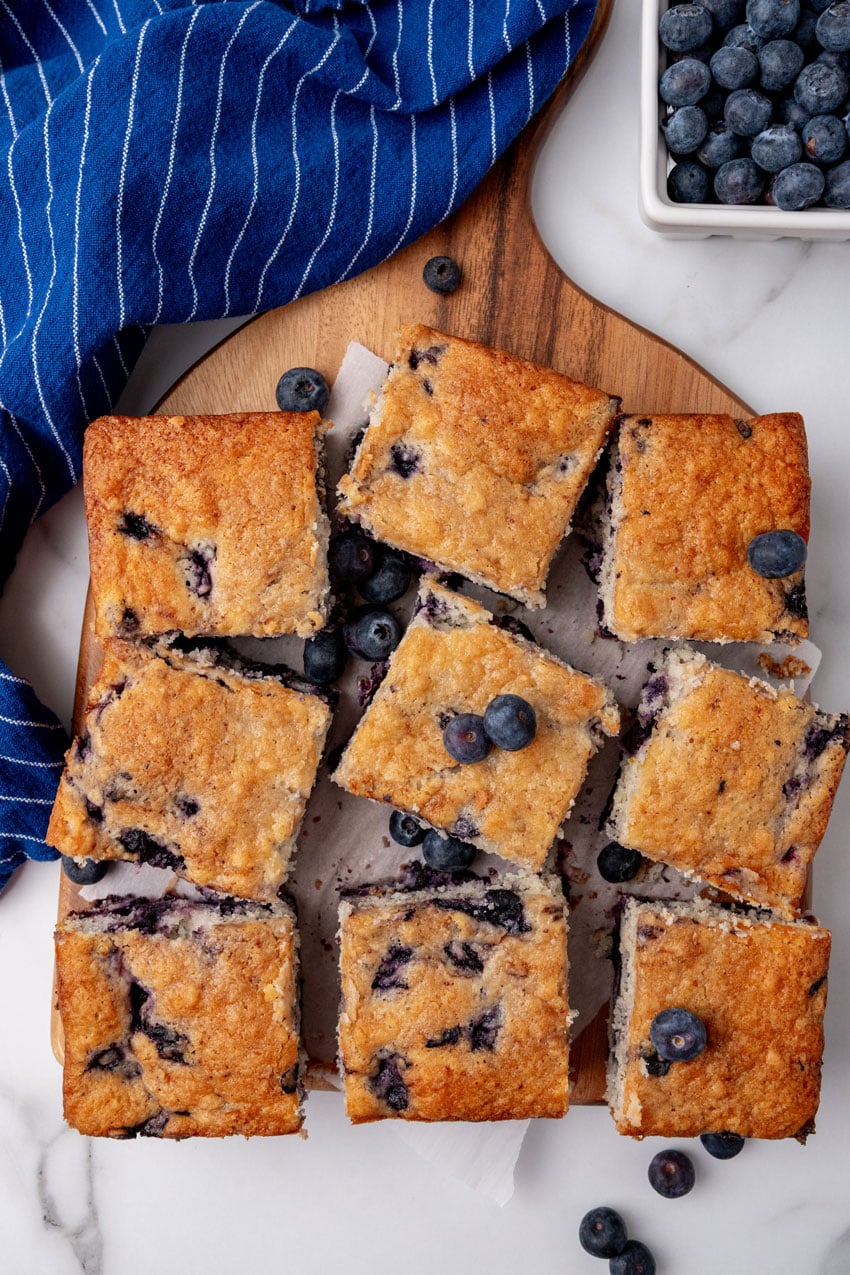 squares of buttermilk blueberry breakfast cake on a wooden cutting board