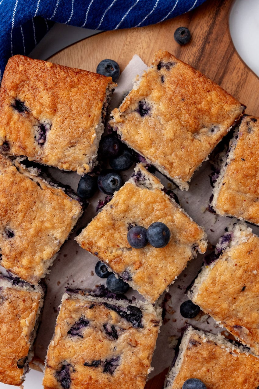 squares of buttermilk blueberry breakfast cake on a wooden cutting board