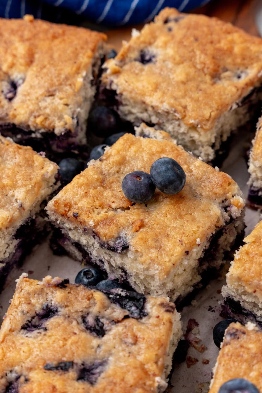 squares of buttermilk blueberry breakfast cake on a wooden cutting board