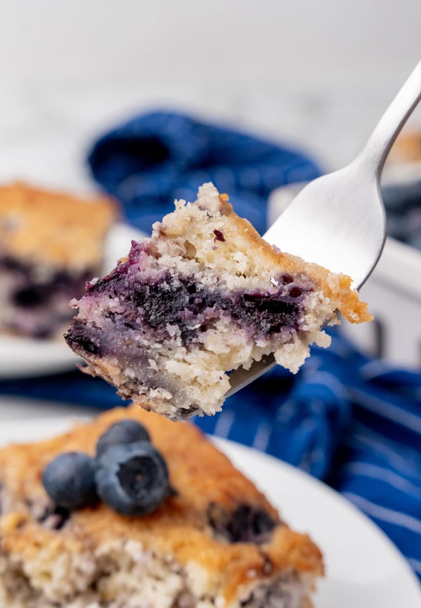 a silver fork holding up a piece of blueberry breakfast cake