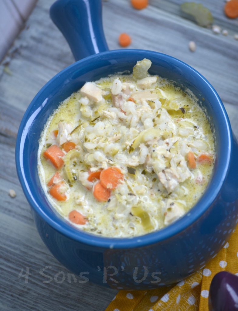 Crockpot Chicken And Pesto Soup in a handled blue ceramic bowl on a wooden background