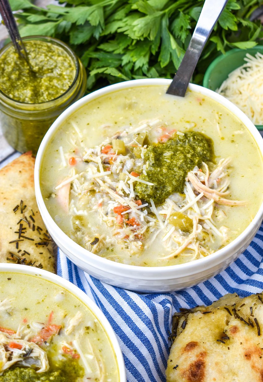chicken pesto soup topped with a dollop of basil pesto sauce in a white bowl