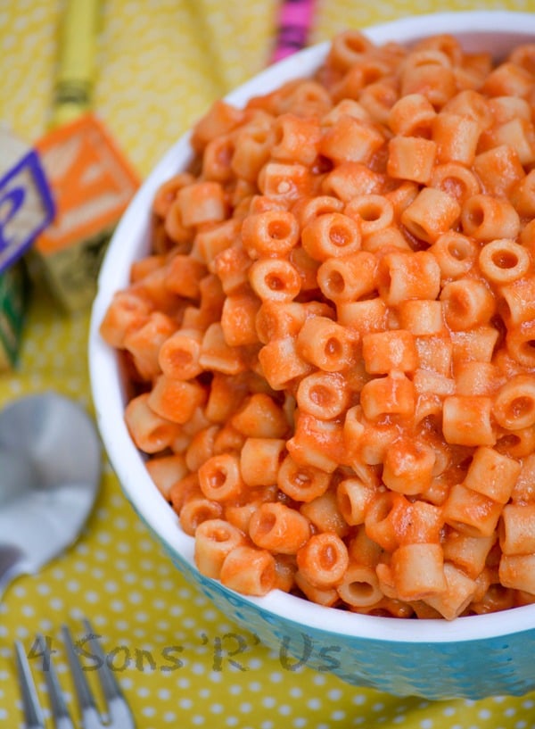 Homemade Spaghetti O's in a white rimmed blue bowl on a yellow background