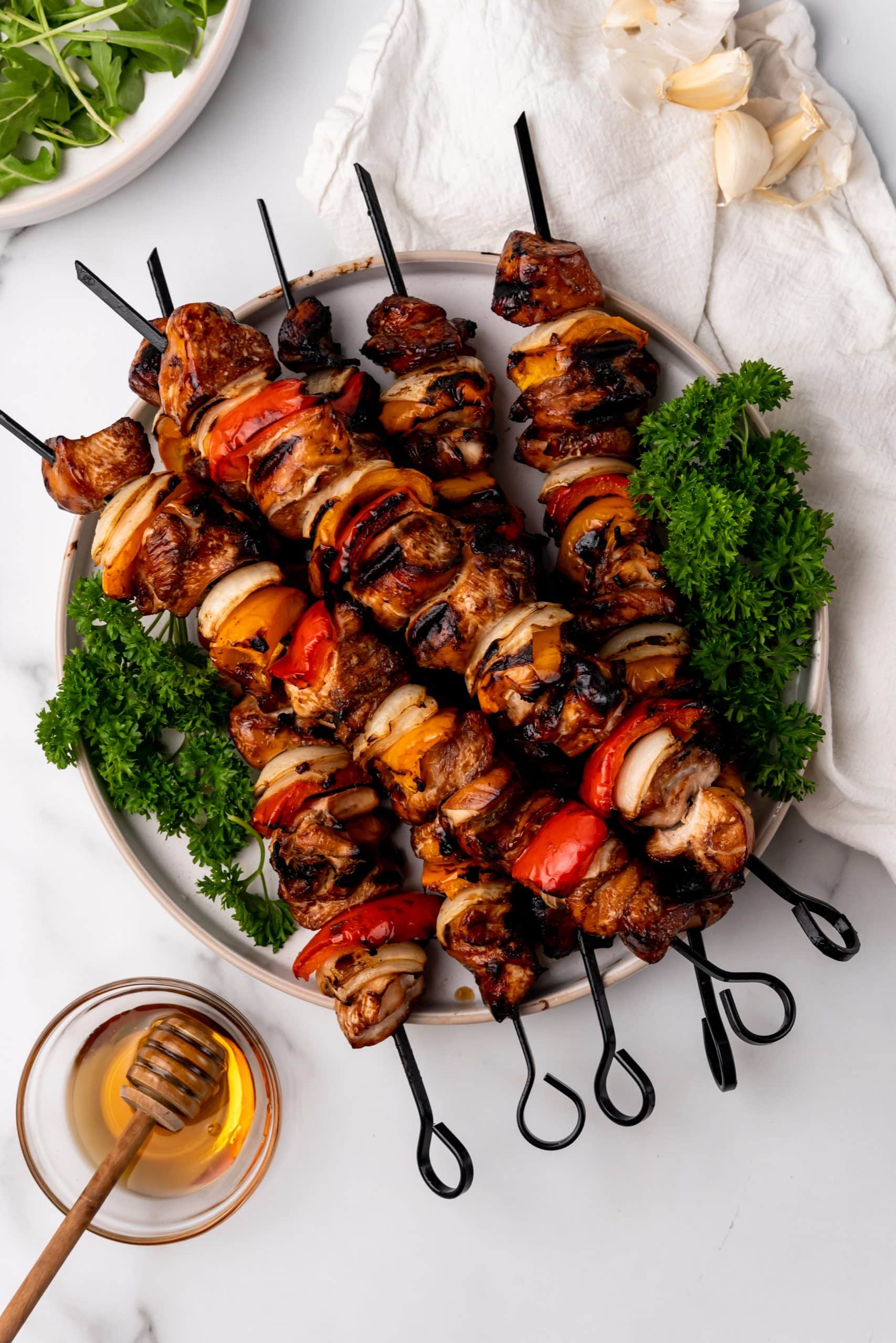 grilled honey garlic chicken kabobs arranged on a lettuce lined white plate