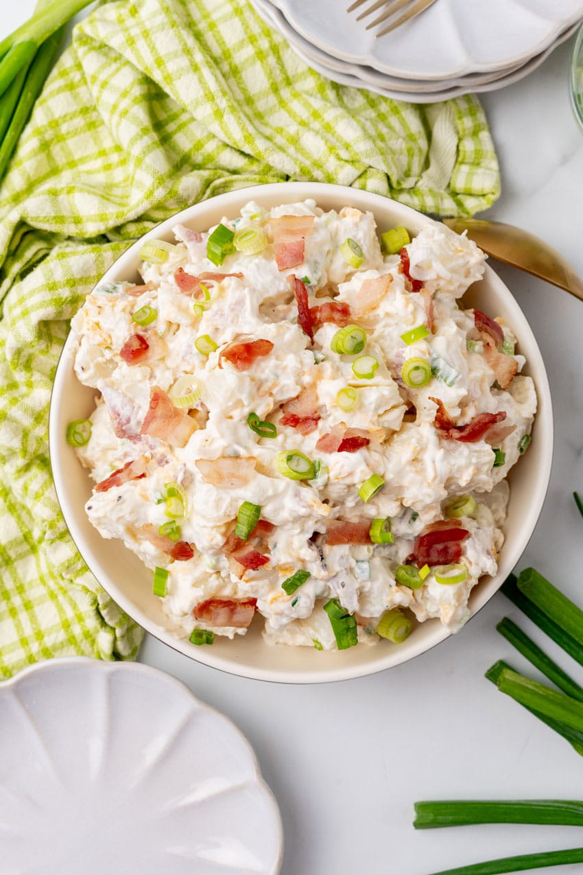 LOADED BAKED POTATO SALAD IN A WHITE SERVING BOWL