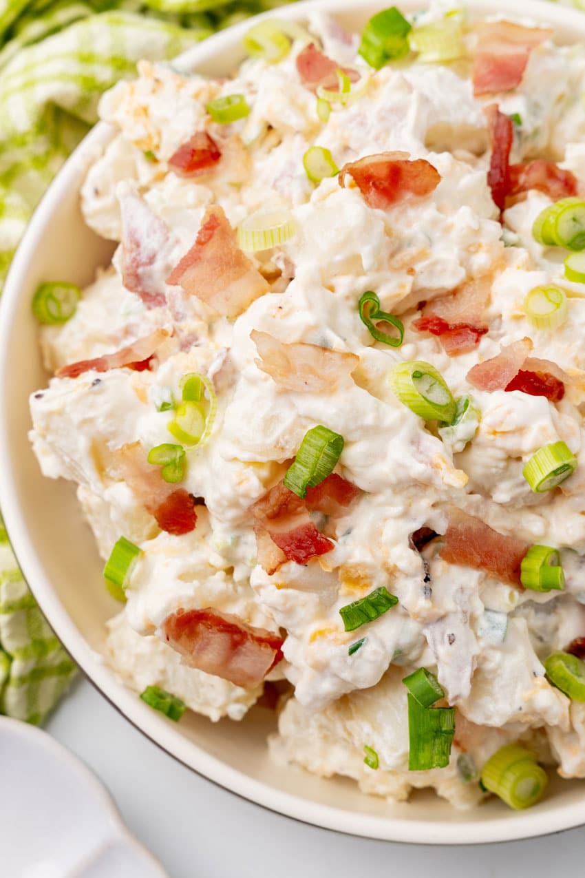 LOADED BAKED POTATO SALAD IN A WHITE SERVING BOWL