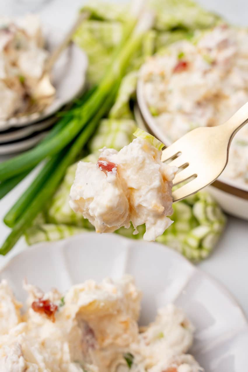 a fork holding up a scoop of loaded baked potato salad
