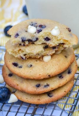 a stack of blueberry cheesecake cookies with white chocolate chips in front of a glass of milk