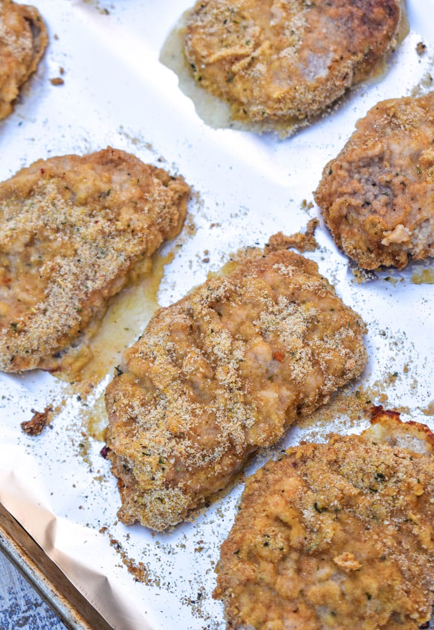 baked breaded pork chops with ranch dressing on a foil lined baking sheet
