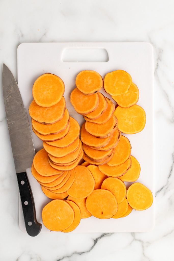 thin slices of sweet potato arranged on a white cutting board