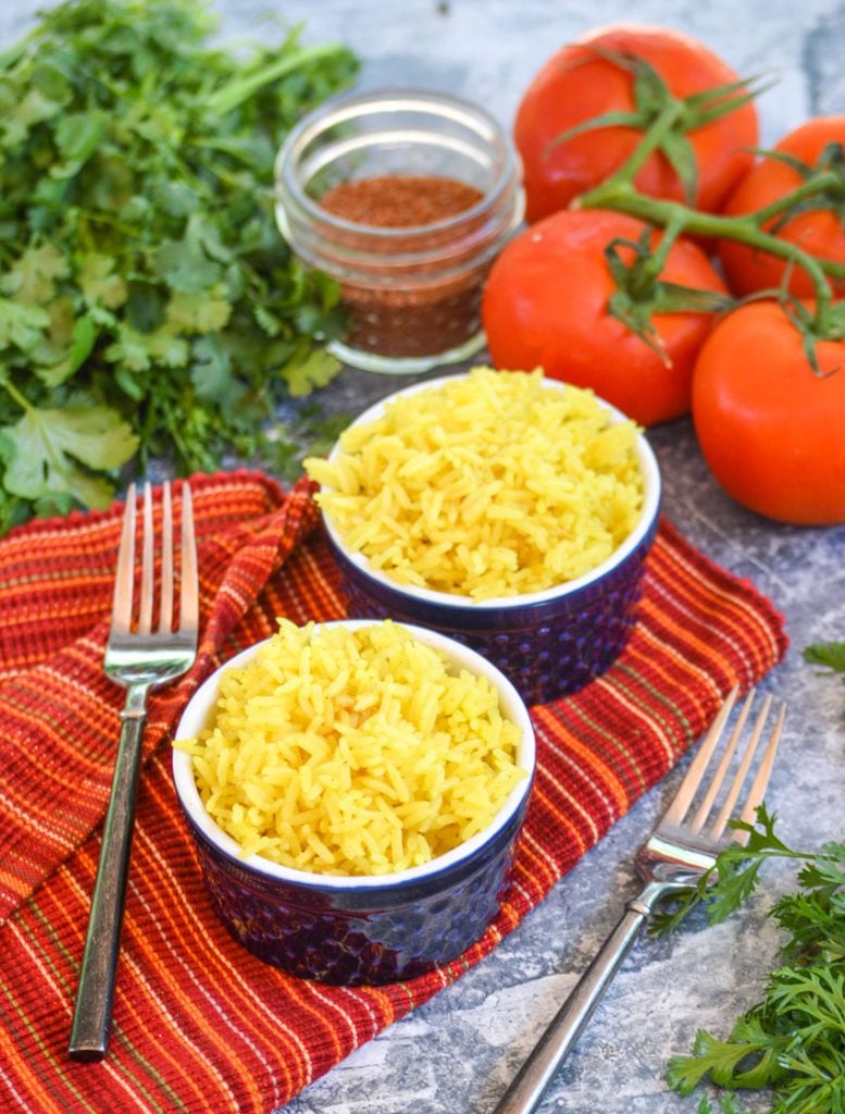 yellow basmati rice in blue ramekins on a cloth napkin with vine ripened tomatoes and fresh cilantro in the background