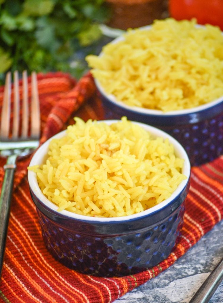 yellow basmati rice in blue ramekins on a cloth napkin with vine ripened tomatoes and fresh cilantro in the background