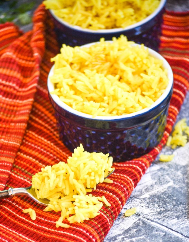 yellow basmati rice in blue ramekins on a cloth napkin with vine ripened tomatoes and fresh cilantro in the background