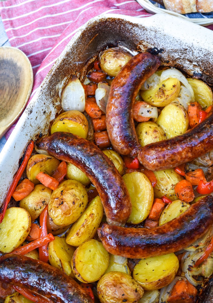 baked Italian sausage and potatoes in a white casserole dish