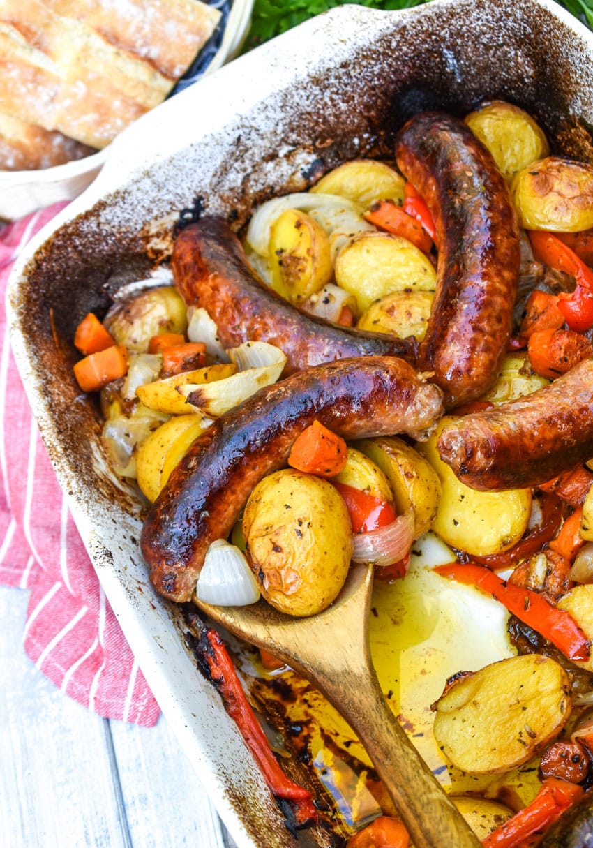 baked Italian sausage and potatoes in a white casserole dish