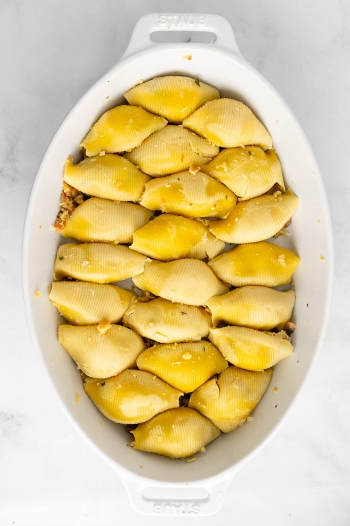 filled cooked shell shaped pasta in a white oval casserole dish