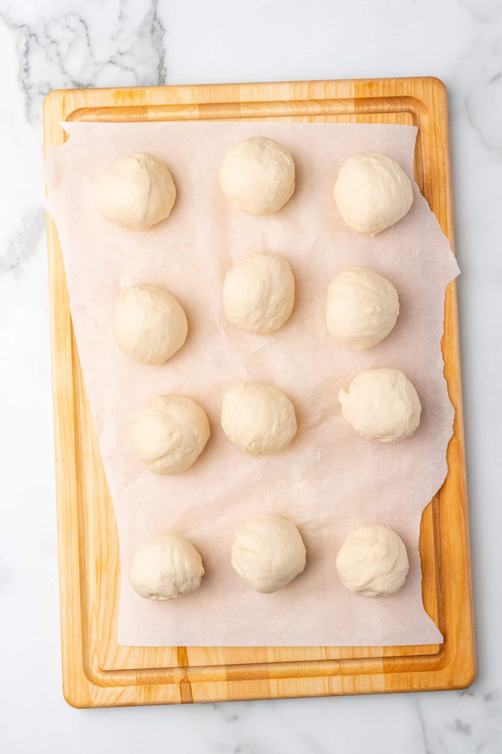 rounded balls of easy pretzel dough on a parchment paper lined cutting board