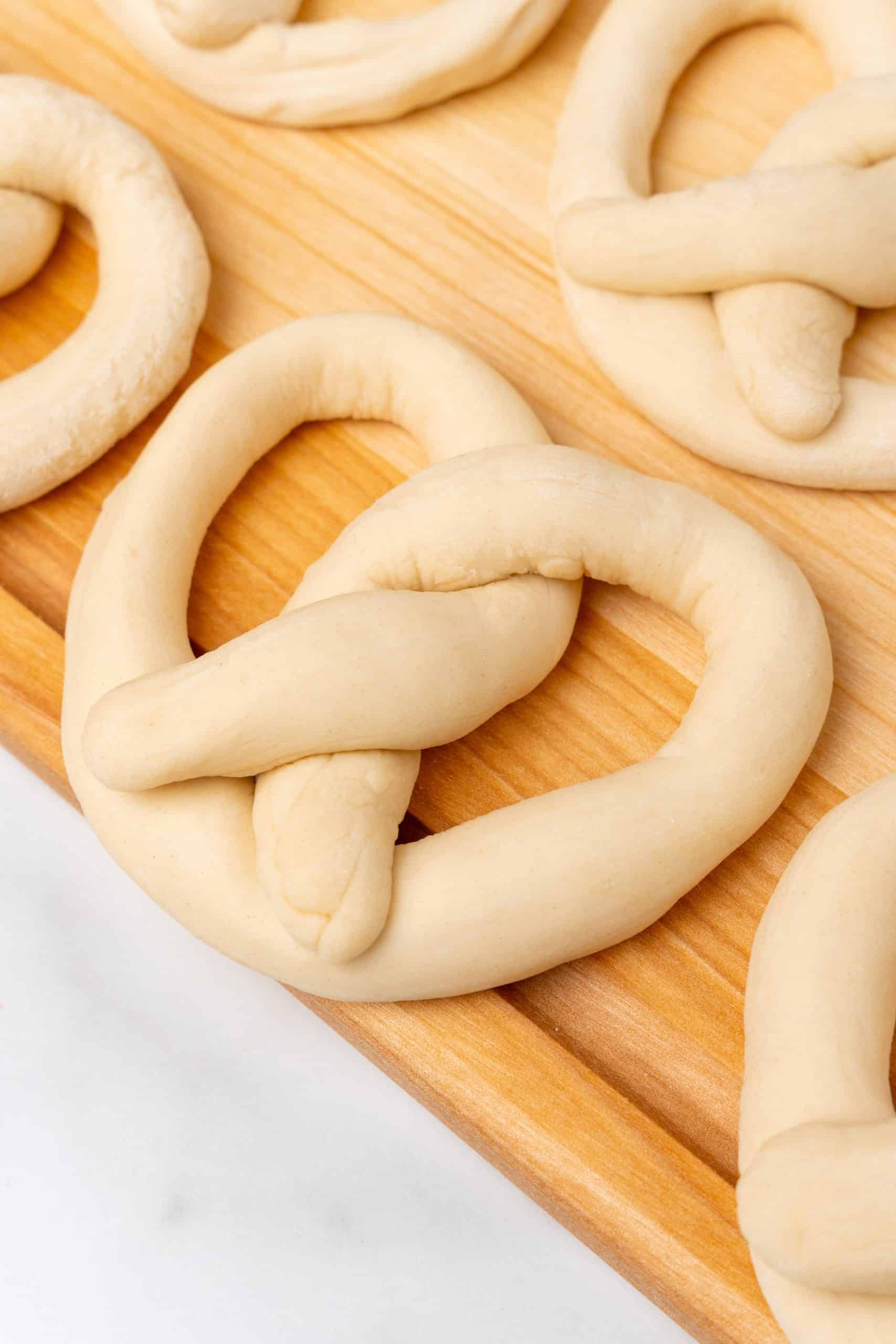 unbaked shaped pretzel dough on a wooden cutting board