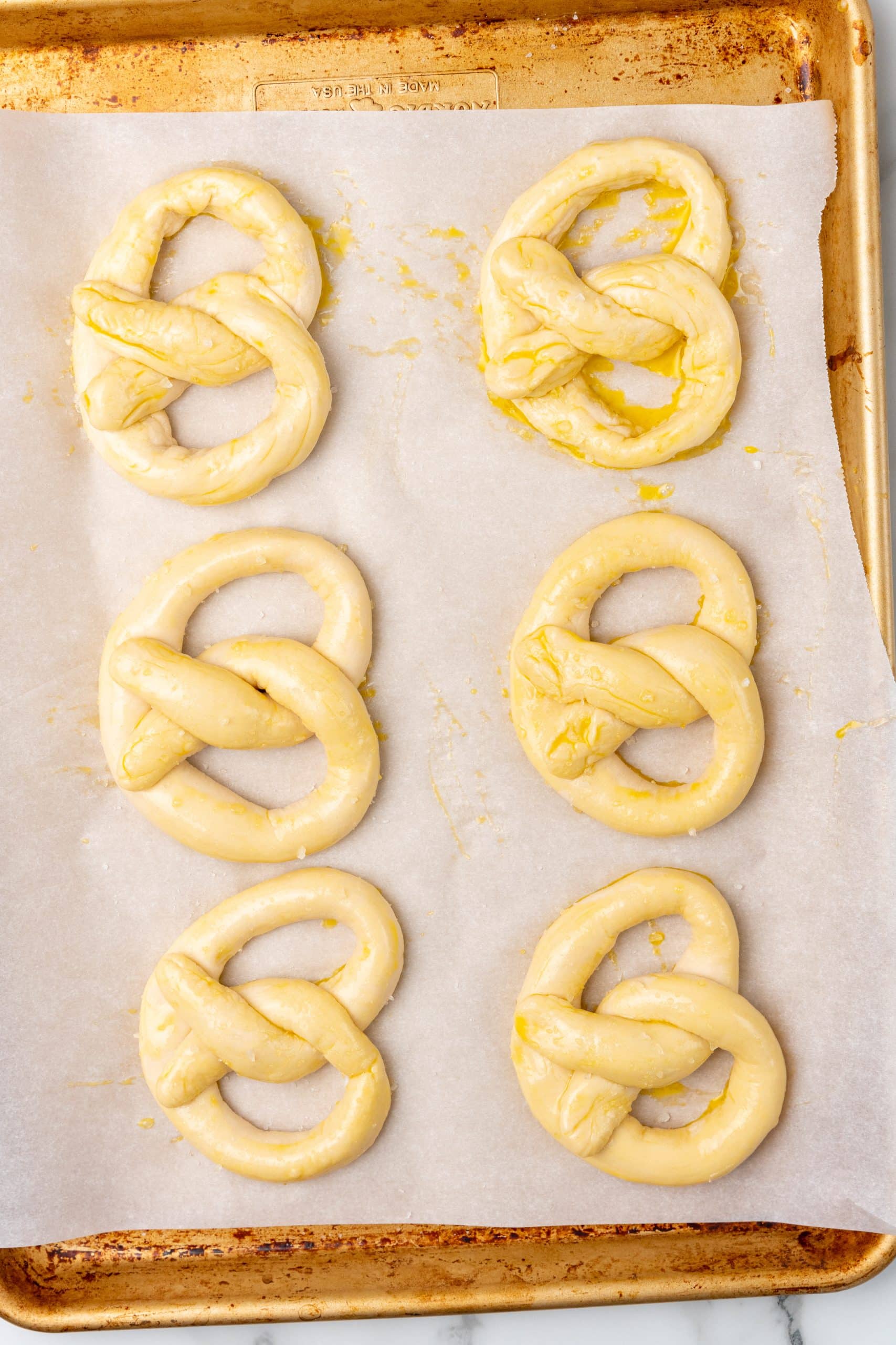 unbaked egg basted 30 minute soft pretzels on a parchment paper lined baking sheet