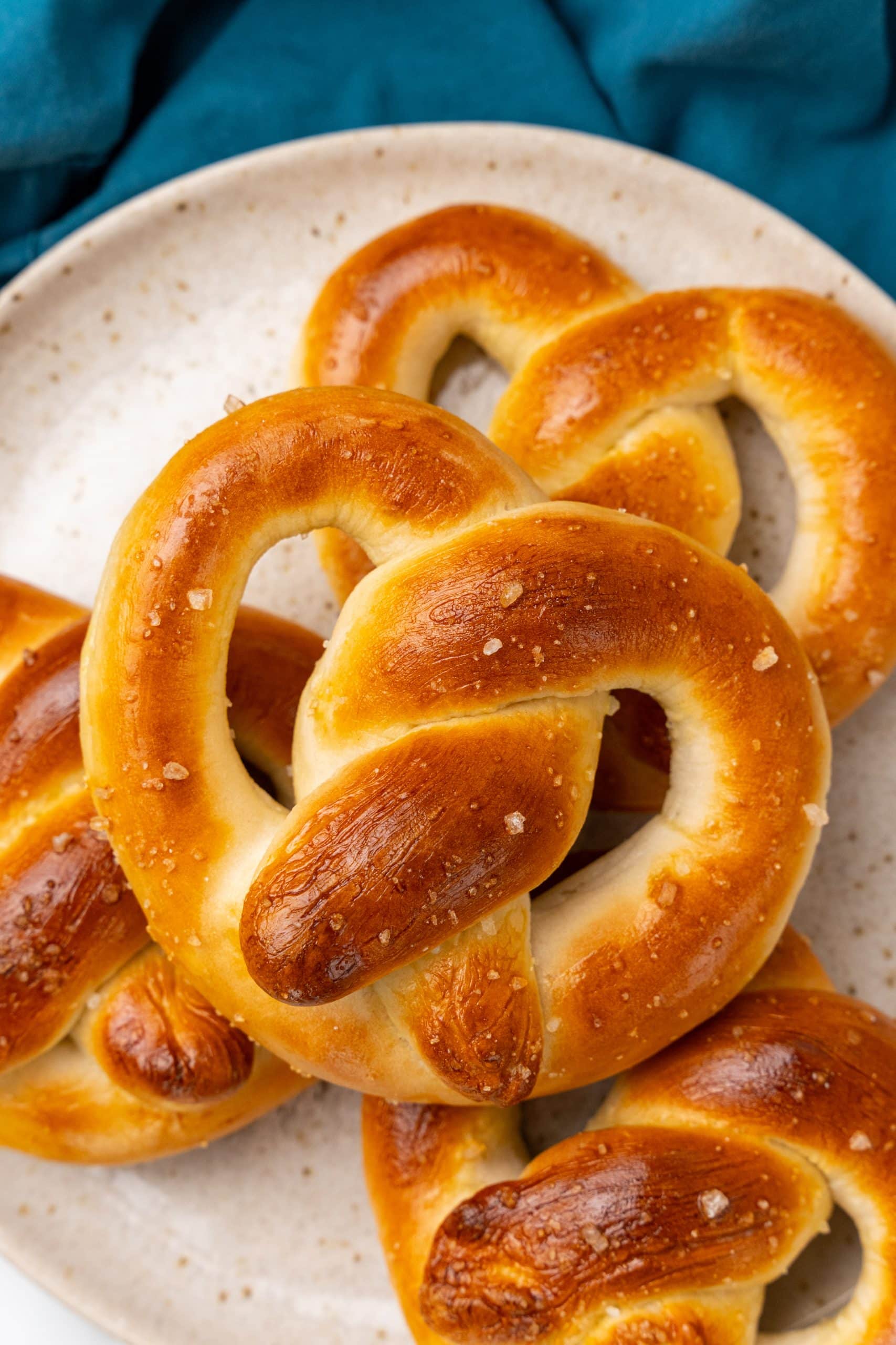 salted homemade pretzels piled on a white plate