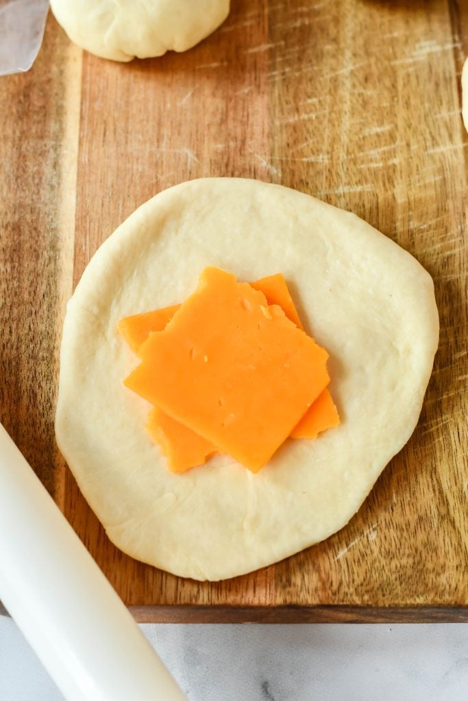 cheeseburger bun dough topped with two squares of sliced cheese