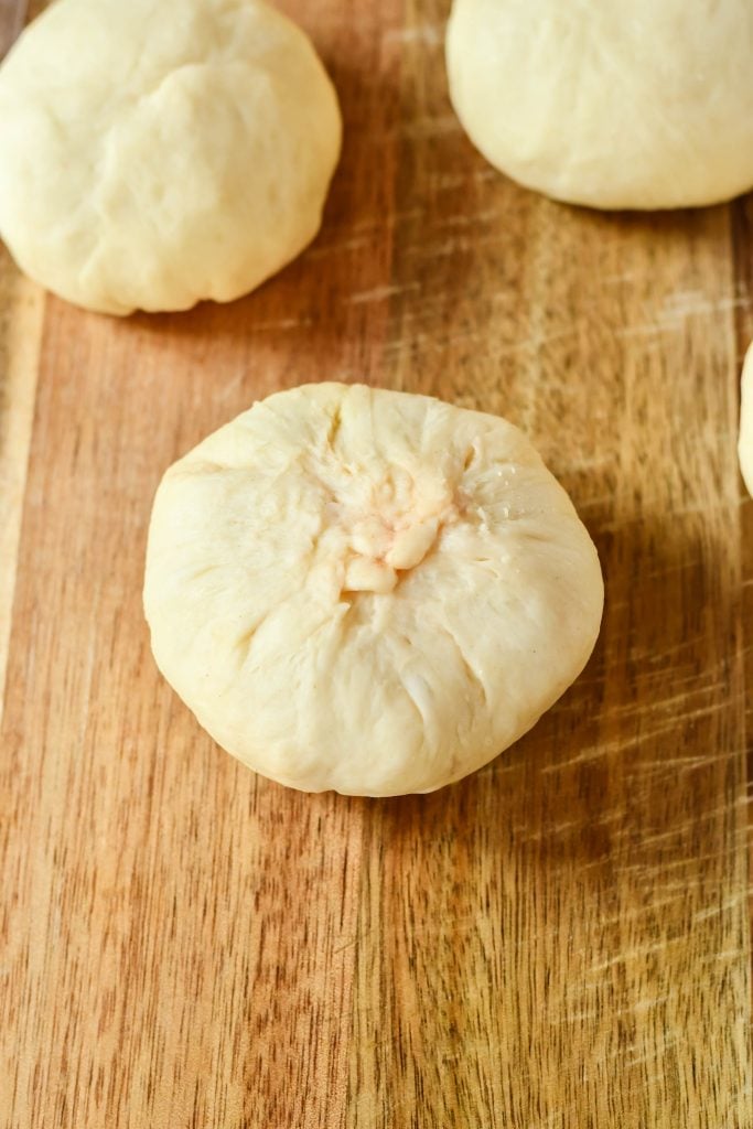 cheeseburger buns stuffed and rolled up on a wooden cutting board