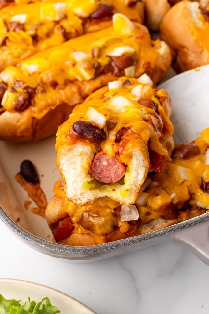 an oven baked hot dog with a bite removed in a casserole dish
