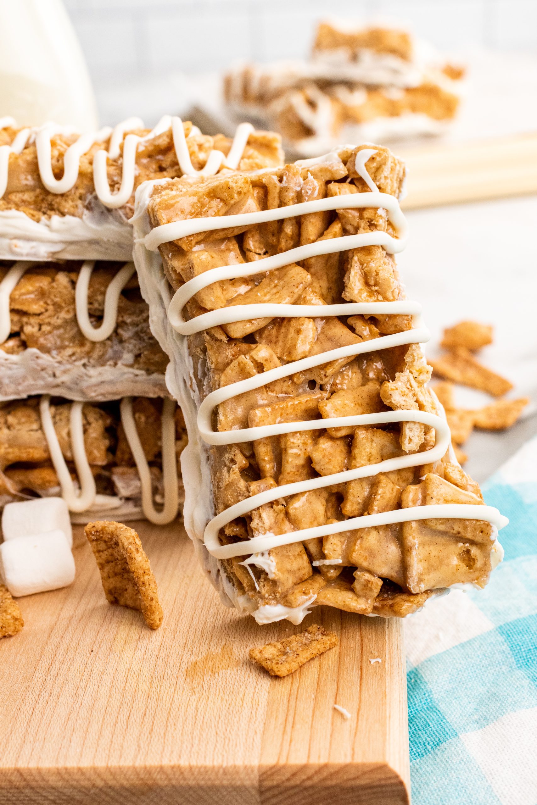 a stack of cinnamon toast crunch cereal bars drizzle with white chocolate on a wooden cutting board