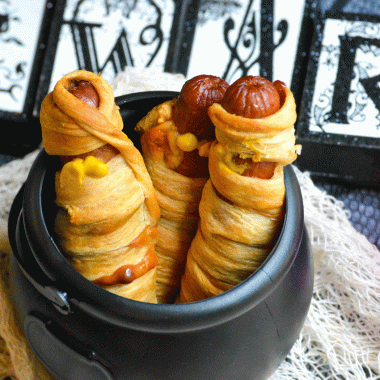 baked mummy dogs in a black plastic cauldron