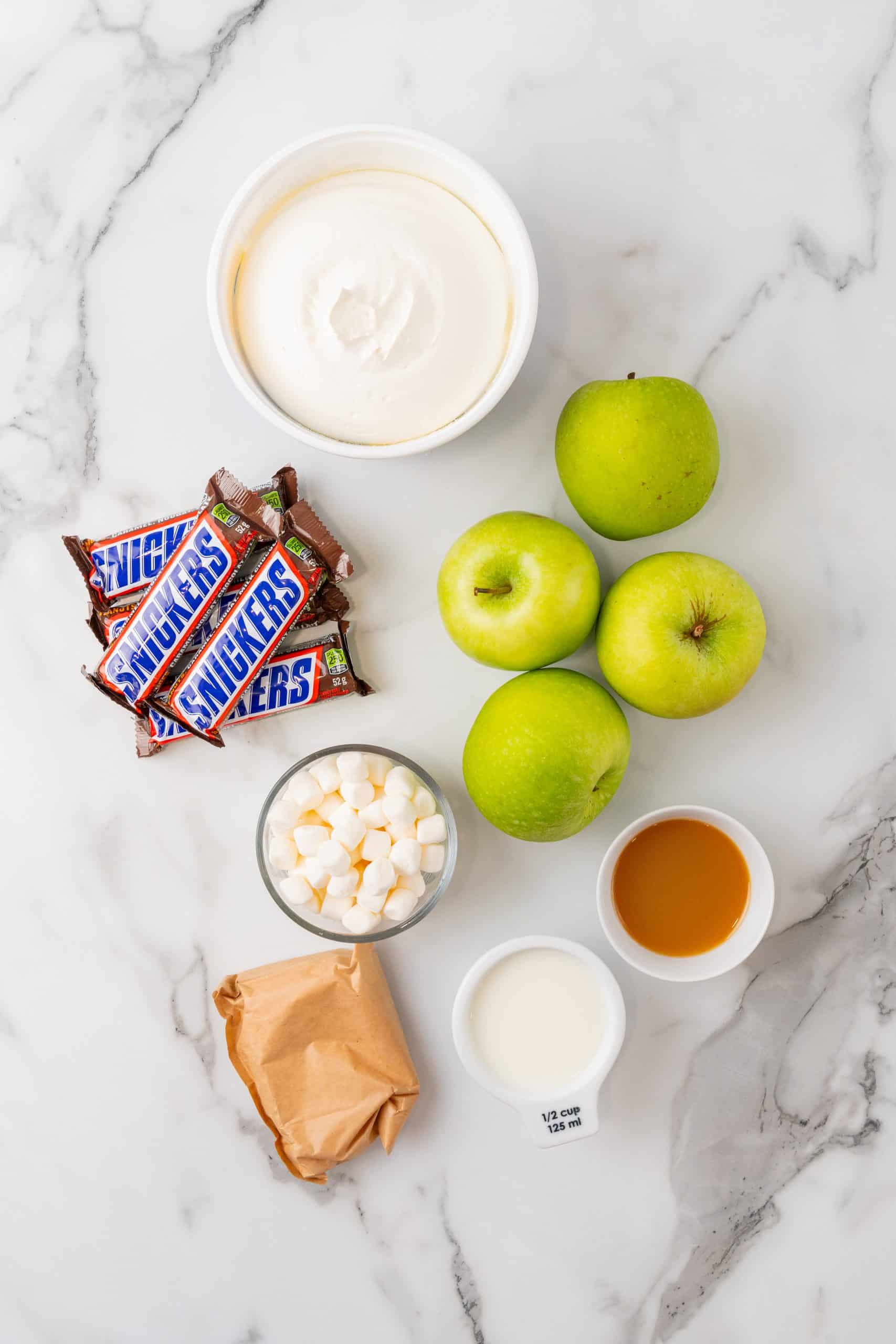 an overhead image showing the measured ingredients needed for a batch of snickers apple salad