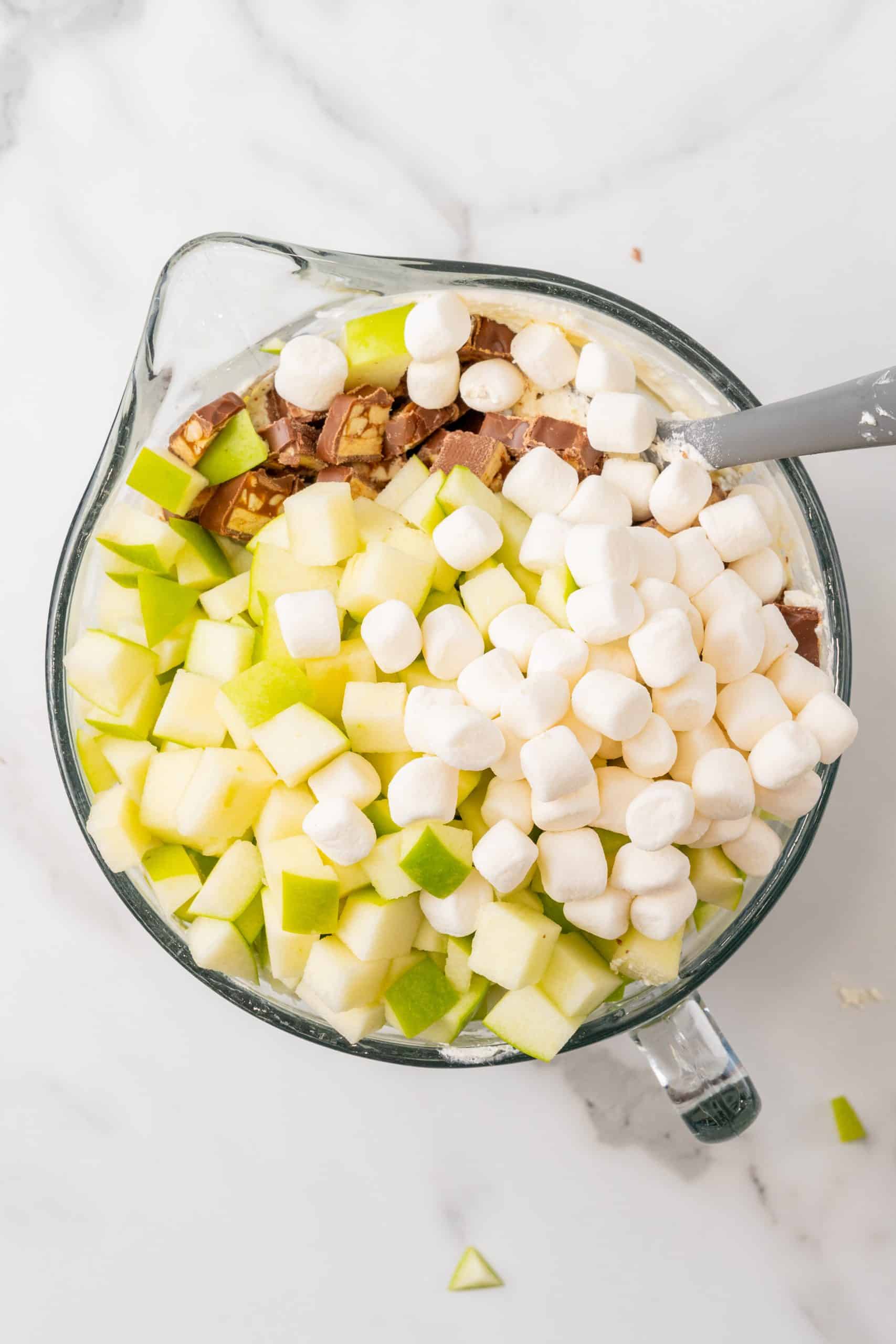 caramel snickers apple salad ingredients in a large glass mixing bowl