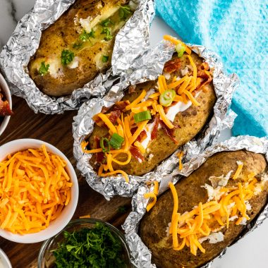 three crockpot baked potatoes arranged in a row and loaded with toppings