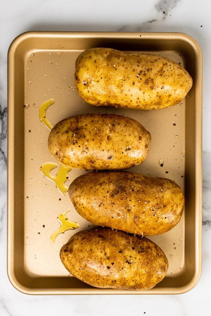 a row of russet potatoes seasoned with olive oil, salt, and pepper