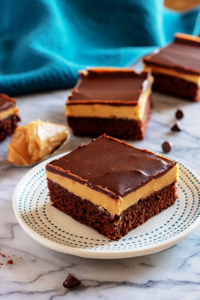 Buckeye Brownie on a white dotted plate with other slices in the back ground and a blue dish cloth