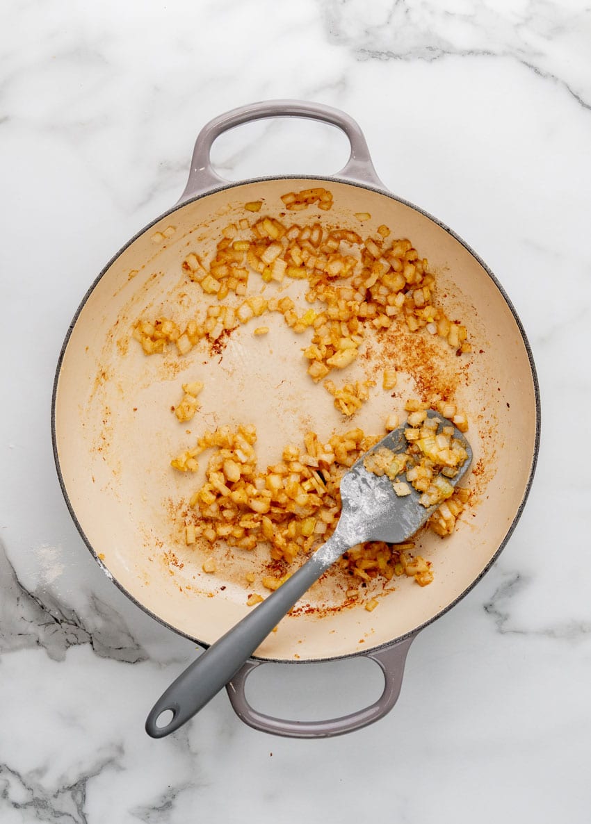 diced onions frying in beef drippings in a large enameled cast iron skillet