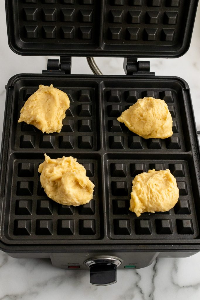 four wafeltjes cookie batter balls on a hot waffle iron