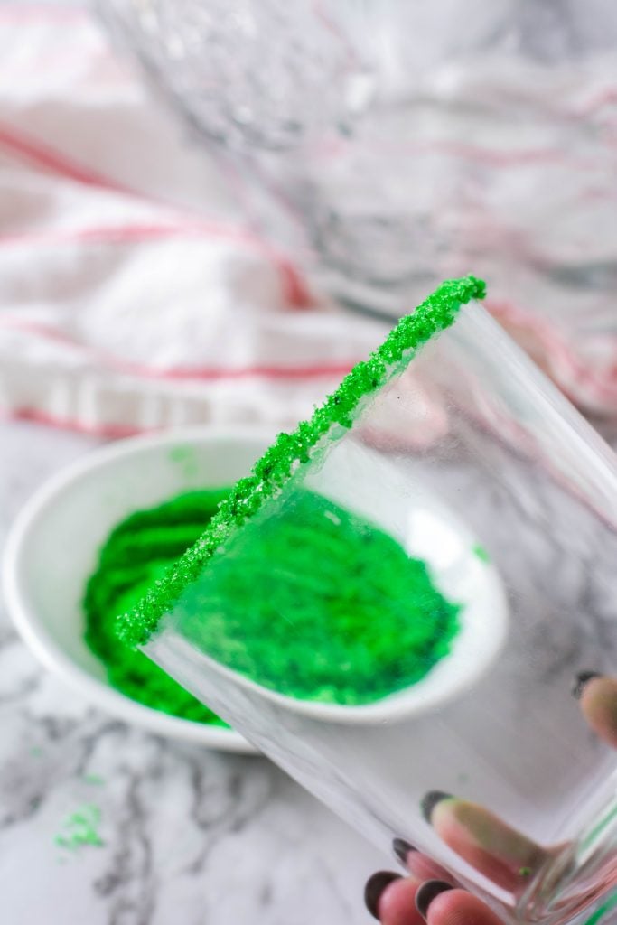 a clear glass shown rimmed with edible food coloring dyed green sugar